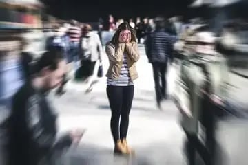 woman holding hands over face with crowds around her